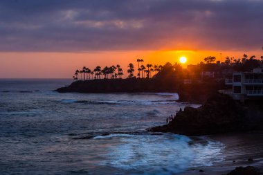 Renkli gökyüzü günbatımı kaya oluşumları ve palmiye ağaçları, dalgıçlar Cove, Laguna Beach, Kaliforniya silüeti çökmesini dalgaları ile güzel kıyı manzarasına