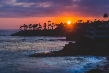 Renkli gökyüzü günbatımı kaya oluşumları ve palmiye ağaçları, dalgıçlar Cove, Laguna Beach, Kaliforniya silüeti çökmesini dalgaları ile güzel kıyı manzarasına