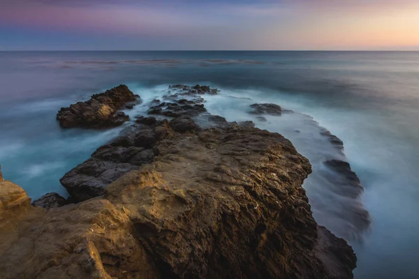 Atemberaubende Langzeitbelichtung Von Glatten Wellen Die Nach Sonnenuntergang Felsformationen Krachen — Stockfoto
