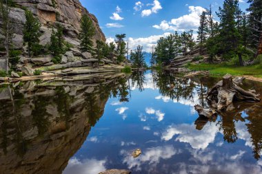 Mavi gökyüzü, bulutlar, dağlar ve ağaçlar, Estes Park, Colorado yansıması ile Gem göl kenarında mükemmel durgun su