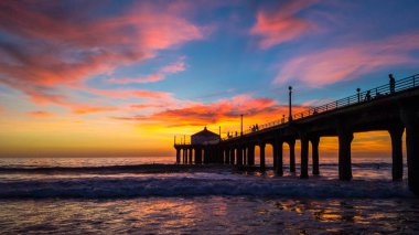 Renkli gökyüzü ve bulutlar üzerinde Manhattan Beach iskelesinden yumuşak dalgalar sahile, Manhattan Beach, Kaliforniya yıkama ile gün batımında