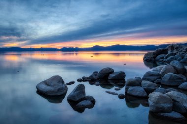 Colorful sky at sunset at Sand Harbor with calm water, beautiful rock formations, and mountains in the background, Lake Tahoe, Carson City, Nevada clipart