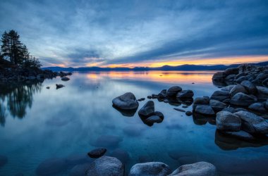 Günbatımında sakin su, güzel kaya oluşumları ve arka plan, Lake Tahoe, Carson City, Nevada dağlarında renkli gökyüzü kum Harbor