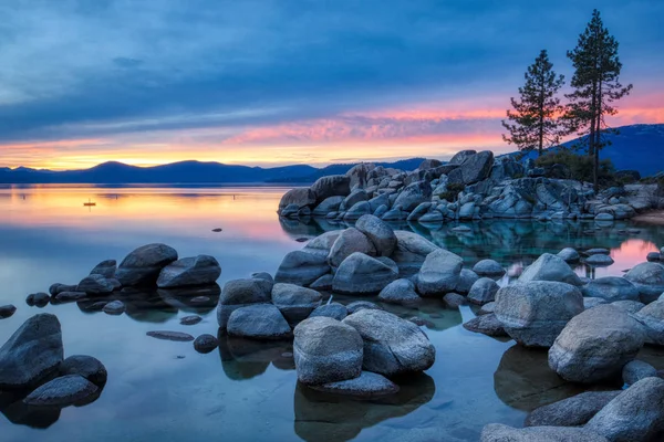 Günbatımında sakin su, güzel kaya oluşumları ve arka plan, Lake Tahoe, Carson City, Nevada dağlarında renkli gökyüzü kum Harbor