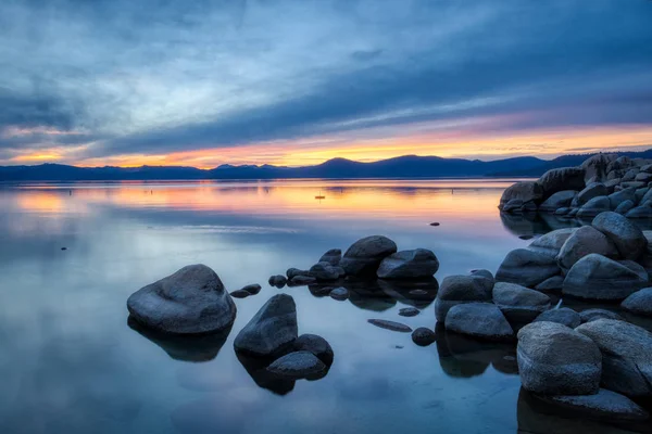 Günbatımında sakin su, güzel kaya oluşumları ve arka plan, Lake Tahoe, Carson City, Nevada dağlarında renkli gökyüzü kum Harbor