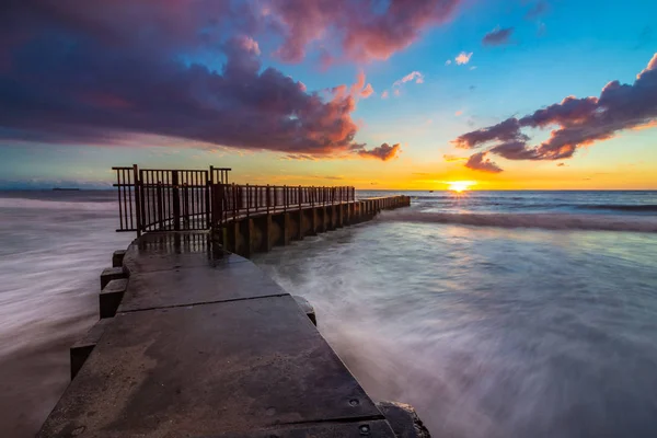 Uzun pozlama fotoğraf renkli bulutlar gökyüzünde, ayak parmakları Beach, Playa Del Rey, California ile gün batımında Mcgurk Beach iskelesi çökmesini dalgaları