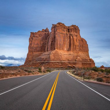 Arches Scenic Drive boyunca görülen devasa kumtaşı kulesi. Başında dramatik fırtına bulutları beliriyor. Arches National Park, Moab, Utah.