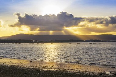 Arousa ada Beach'de Bao üzerinde gündoğumu, cumulus bulutları arasında yükselen güneş ışınları