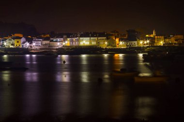 Geceleyin Arousa Adası Köyü 'nün aydınlanmış kıyı şeridi.
