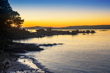 Punta Cabalo Burnu Arousa Adası 'nda, insanlar gün batımını parlayan deniz fenerinden izliyorlar.