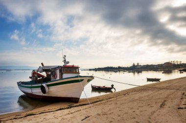 İspanya, Galiçya 'daki Arousa Adası' ndaki fırtınalı bulutların altında Cabodeiro sahilinde midye suyu ve balıkçı tekneleri.