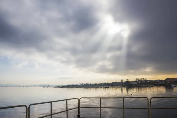 Sunbeams rising from the stormy sky over the calm sea of Arousa Island, Galicia, Spain