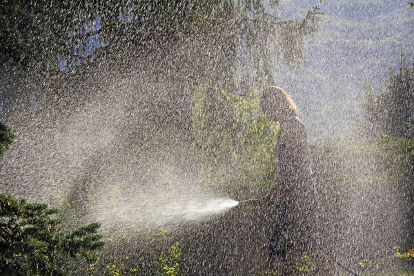 A young woman Watering a lawn in the yard of the house, a background sunlight