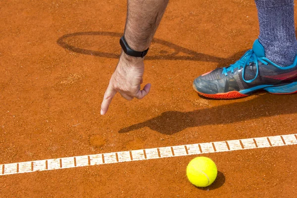 Tennispelaaja näyttää kappaleen tenniskentällä — kuvapankkivalokuva