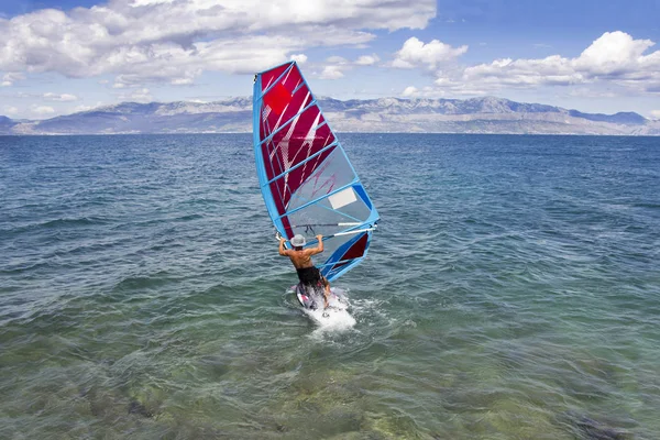 Jovem windsurfista nas ondas do mar — Fotografia de Stock