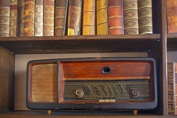 Velho rádio vintage na prateleira de madeira com livros — Fotografia de Stock