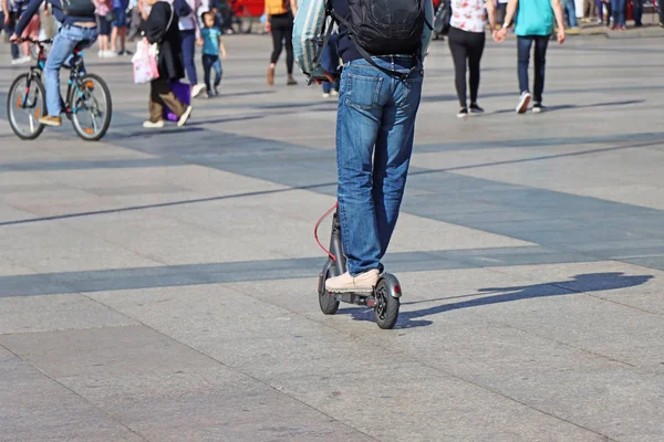 Hombre montando un patinete scooter en la plaza de la ciudad — Foto de Stock