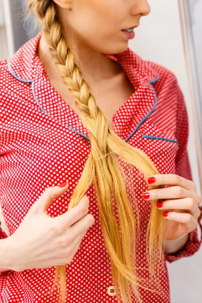 花式时尚金发发型在家居概念 女人穿着粉红色睡衣做上金发辫子 — 图库照片