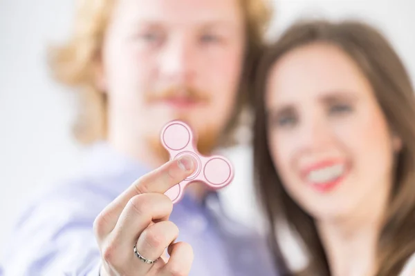 何百万人ものカップルは単純なおもちゃに驚かされています 男と女はピンクのフィジェットスピナーで遊んで 傾向を理解しようとして — ストック写真
