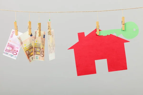 ランドリー線上灰色の背景に緑色のキーと紙幣現金と赤い家がハングします ホーム コンセプトの売買 — ストック写真