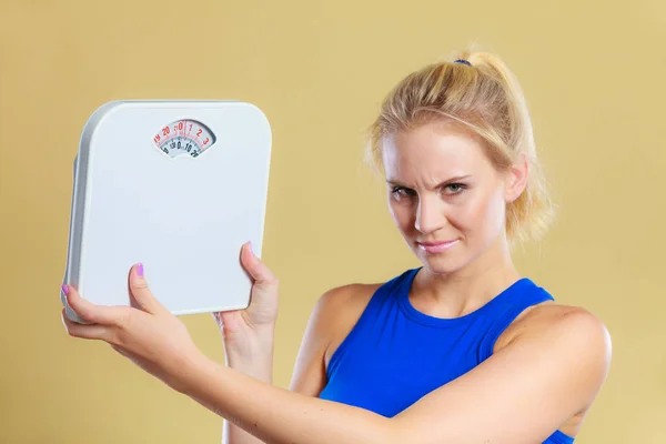 Fit fitness woman with scale. Frustrated angry blonde girl holding weight scales. Time for slimming weightloss, diet and healthy lifestyles concept