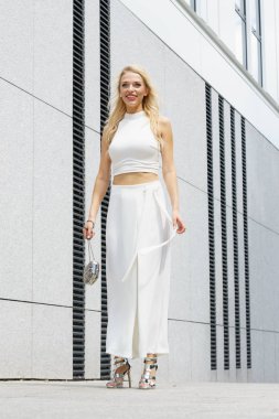 Elegant fashionable woman presenting trendy urban outfit. White crop top and trousers culottes. clipart