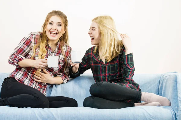 Duas Amigas Sentadas Juntas Sofá Conversando Bebendo Chá Café Divertindo — Fotografia de Stock