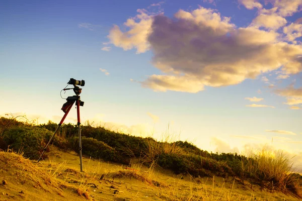 Professional camera taking film video or shooting images pictures on sandy beach dunes