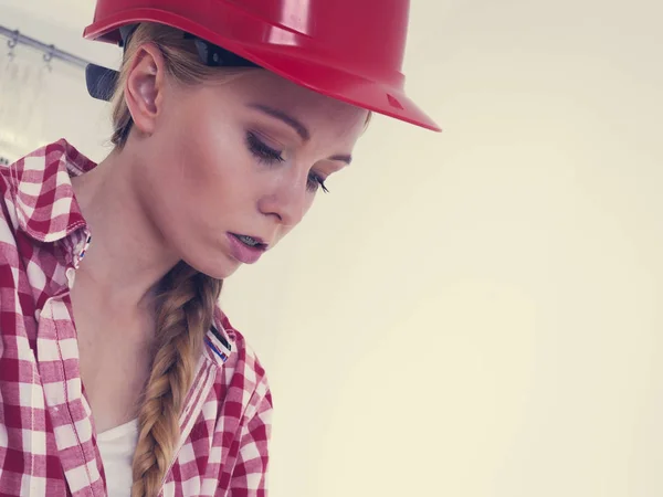 Konzentrierte Bauarbeiterin Blickt Skeptisch Auf Etwas Mit Rotem Schutzhelm — Stockfoto