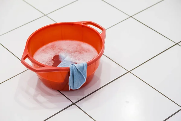红碗用洗涤剂或肥皂和水与布站在瓷砖地板 — 图库照片