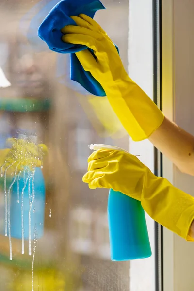 ラグとスプレー洗剤で黄色の手袋のクリーニングウィンドウペインの女性の手 清掃コンセプト — ストック写真