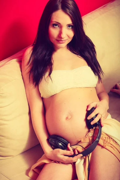 宝贝听音乐概念的积极方面 戴着耳机在孕妇的肚子上的女人 — 图库照片