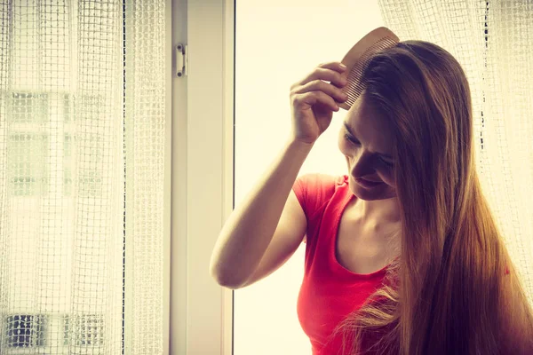 早上例行的概念 女人坐在窗台上梳着长长的黑头发用梳子 — 图库照片