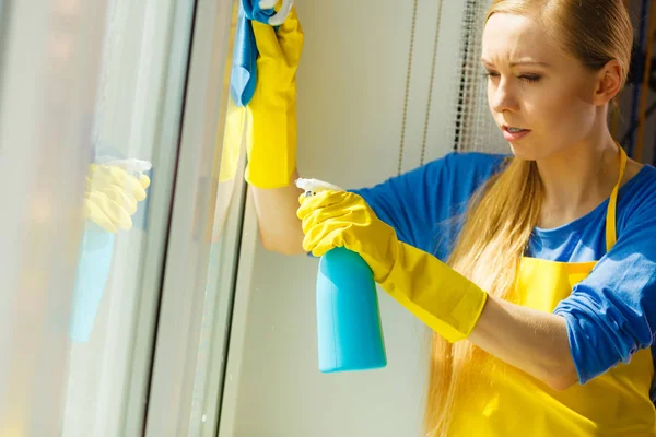 穿着黄色手套的年轻女子用蓝色抹布和喷雾洗涤剂清洗窗户 春季清洁 家务活概念 — 图库照片