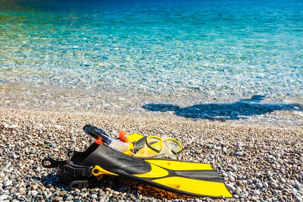 石のビーチの海岸に横たわっているシュノーケリング用具のフリッパーとシュノーケリング用マスクチューブ 夏休み水泳楽しいコンセプト — ストック写真