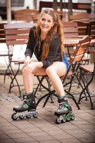町に座ってローラースケートを着て幸せな若い女性 夏の間 女性はスポーティーさを楽しんでいる — ストック写真