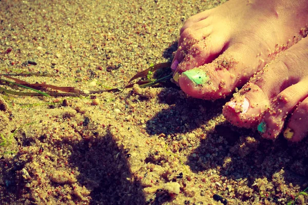 很好的照顾女人脚与海滩上彩色指甲油 — 图库照片