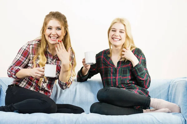 Duas Amigas Sentadas Juntas Sofá Conversando Bebendo Chá Café Divertindo — Fotografia de Stock