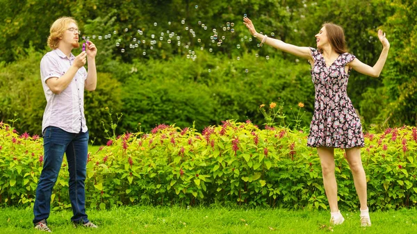 幸せな面白いですヒップスターカップル遊び一緒に吹いて石鹸泡屋外で春の公園 — ストック写真