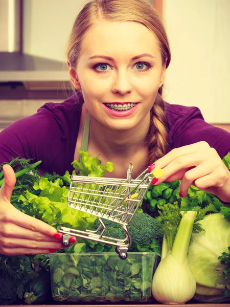 健康的なダイエット食品のコンセプトを購入します 小さなショッピング カート トロリーを保持多くの緑の野菜を持っている台所の女 — ストック写真