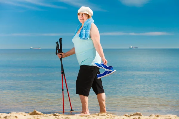 练习北欧走在海边 享受阳光灿烂的夏天的一天的活跃老年女性的女高管 老年健康的生活方式 — 图库照片