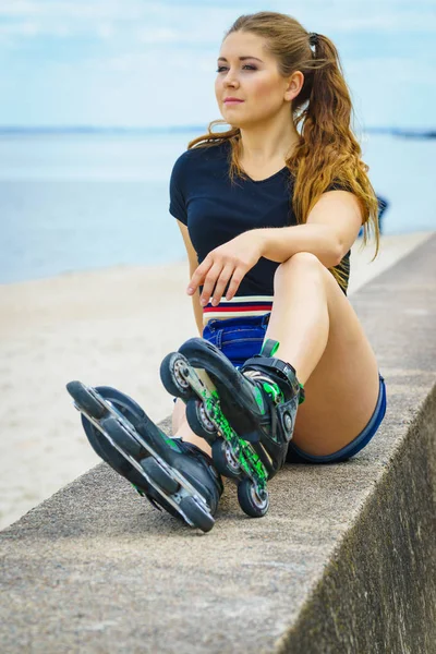 乗車後にリラックスしたローラースケートを身に着けている魅力的な若い女性 海岸で夏の間はスポーティを楽しんでいる女性 — ストック写真