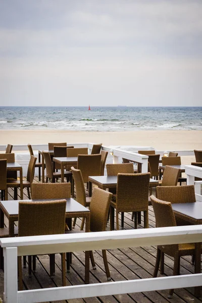 海の水の近くの屋外カフェ デザイン ビーチでのリラクゼーションの場所です 多くの空のテーブルと椅子 — ストック写真