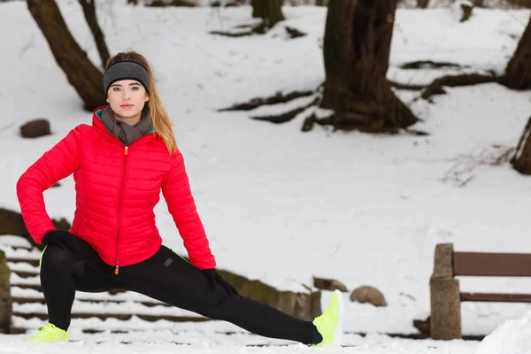 户外运动 运动服创意 冬季穿着保暖运动服的妇女在室外锻炼伸展腿 — 图库照片