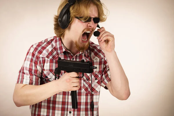マイクでヘッドフォンを装着した銃を持ったビデオコンソールで遊んでいるオタク青年 ゲームゲーマーの概念 — ストック写真