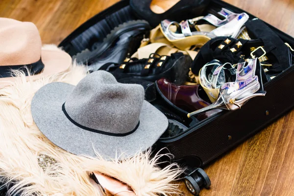 Luggage filled with high heels shoes and stylish fashionable hats. Female clothing packed up.