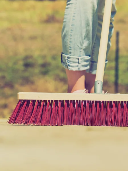 无法辨认的女性使用大扫帚清理后院庭院 — 图库照片