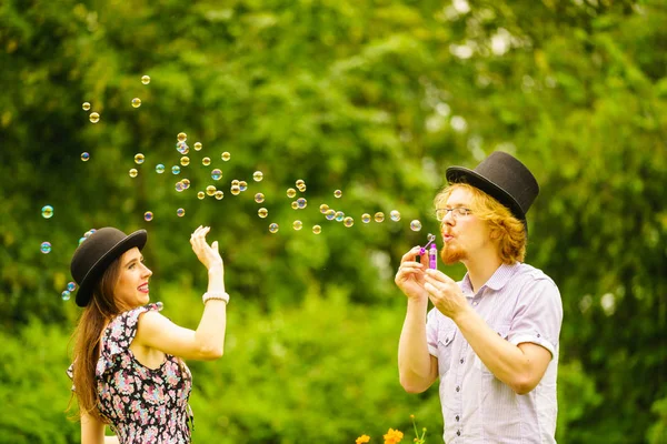 幸せな面白いですヒップスターカップル遊び一緒に吹いて石鹸泡屋外で春の公園 — ストック写真