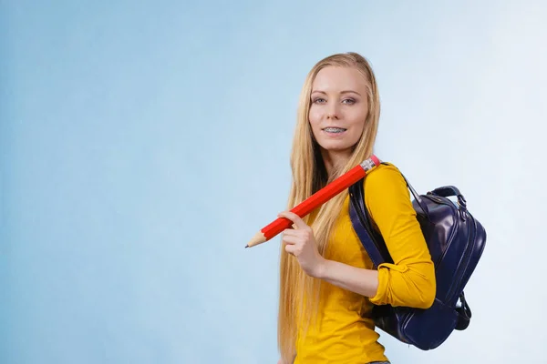 幸せな若いですブロンドティーン女の子行きます学校や大学へ行きますバックパックを身に着けていると保持大鉛筆 — ストック写真