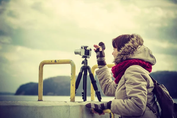 カメラを使って写真を撮る秋の天気の間に海岸線を歩く余暇を持つ女性 — ストック写真